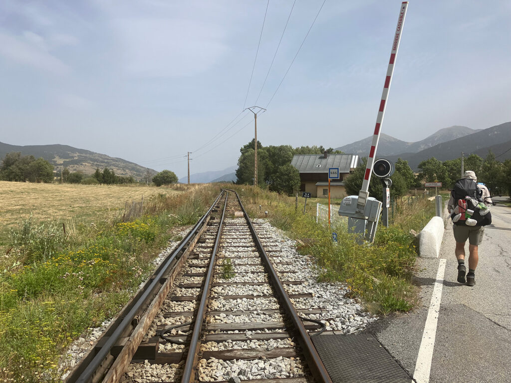 Bert walking on the road, crossing the railway.